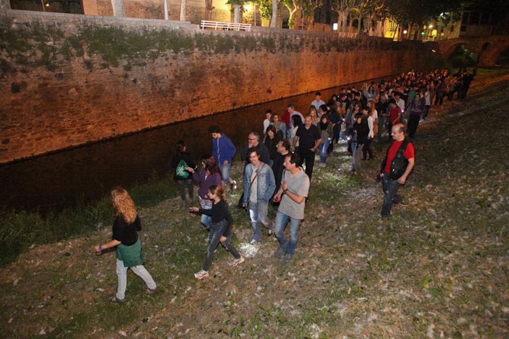 a group of people walking at night along a wall