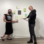 two people pointing at sold artwork