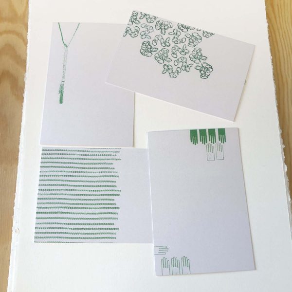 4 white and green postcards on a table