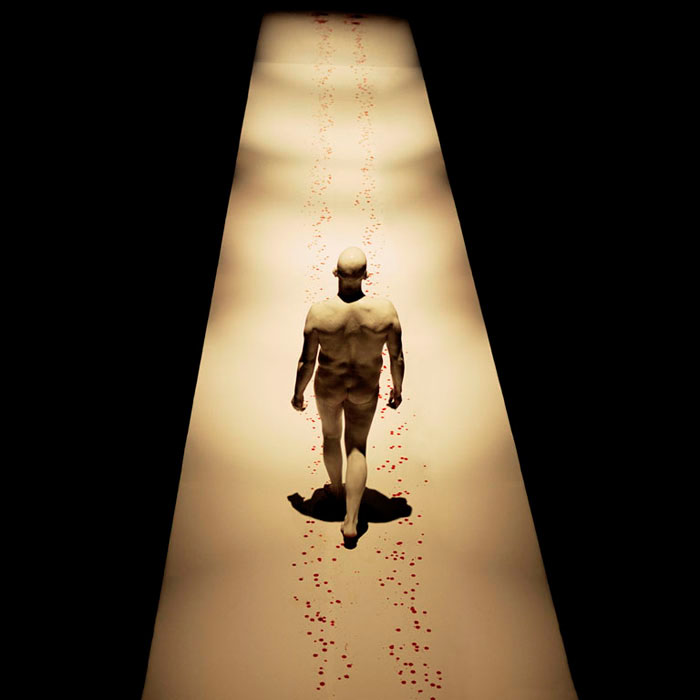 nude man walking down a runway with blood spots